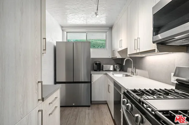 a kitchen with stainless steel appliances a sink stove top oven and cabinets