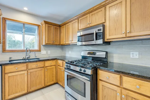 a kitchen with granite countertop cabinets stainless steel appliances a sink and window