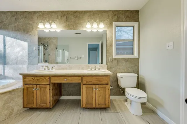 a spacious bathroom with a toilet a sink and a mirror