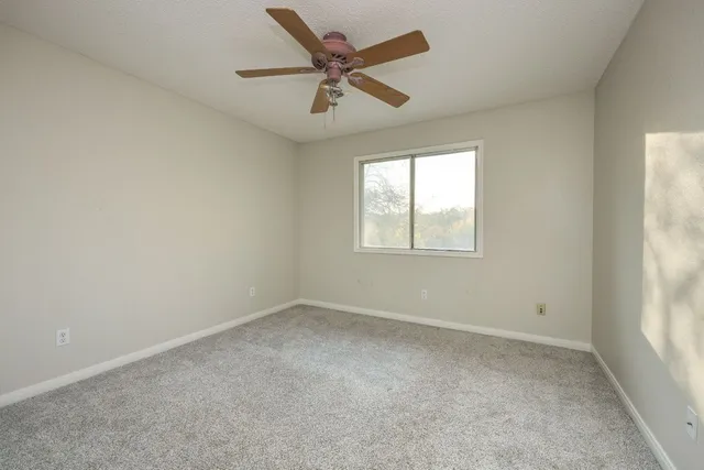an empty room with a window and a ceiling fan