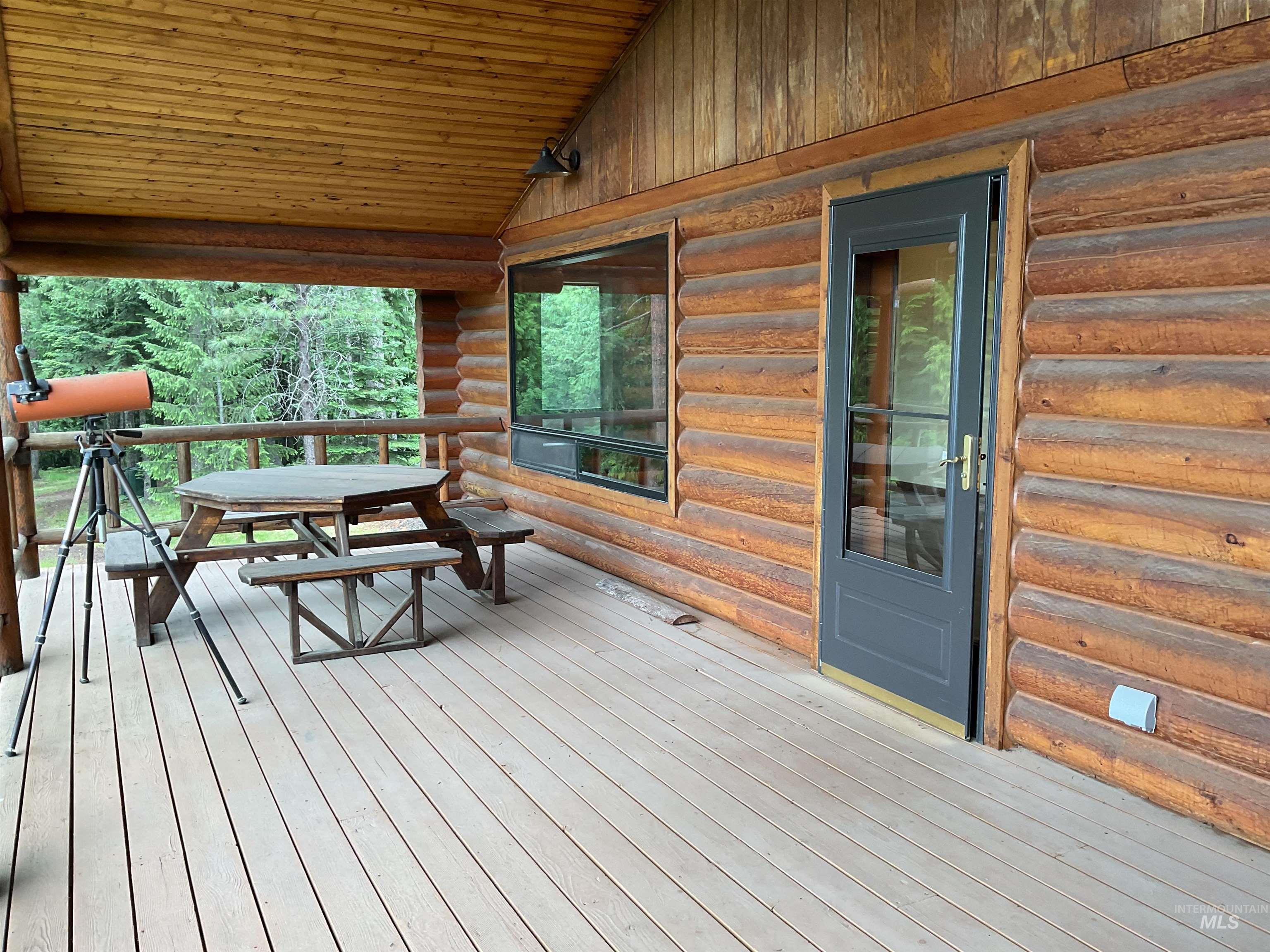 6125 Freeman Creek Road Lenore, ID 83541 - Photo 23 of 44 Expansive log cabin-style deck featuring wood-finish flooring, a full outdoor kitchen with stainless steel appliances and stone-finish cabinetry, rustic log railing, and a natural wood plank ceiling