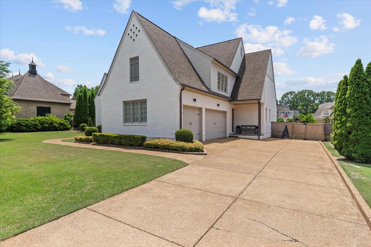 View of side of home featuring driveway, a shingled roof, and a garage