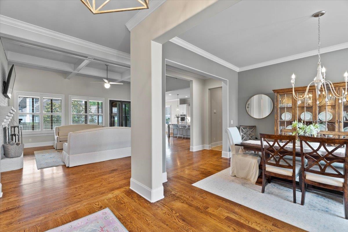 Dining space featuring coffered ceiling, a chandelier, crown molding, wood finished floors, and ceiling fan