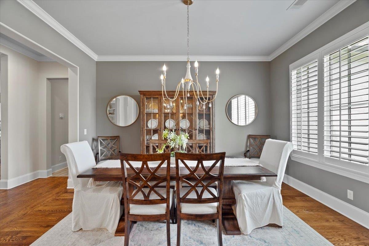 Dining room with a chandelier, ornamental molding, and wood finished floors