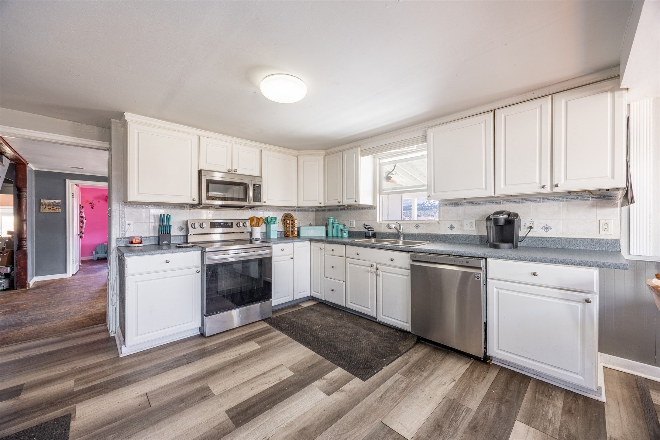 504 North Cable Road Anaconda, MT 59711 - Photo 4 of 34 Kitchen featuring white cabinetry, tasteful backsplash, stainless steel appliances, a sink, and dark wood-style floors