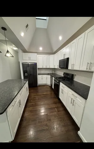 a large kitchen with kitchen island a sink a counter top space and cabinets