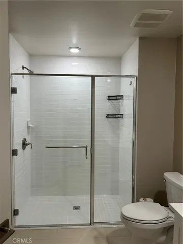 a bathroom with a shower a toilet and a glass door