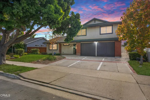 a front view of a house with a garden and trees