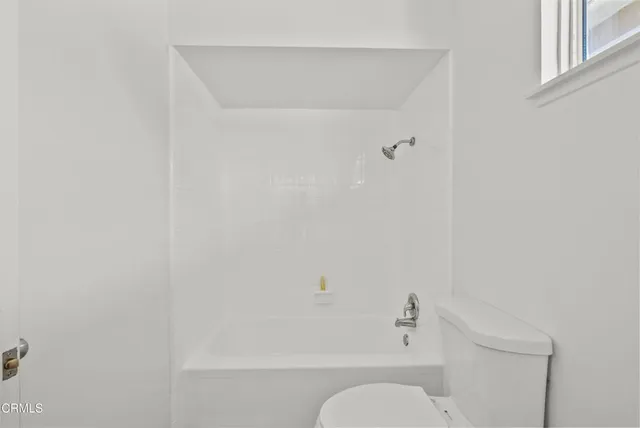 a white toilet sitting next to a white tub