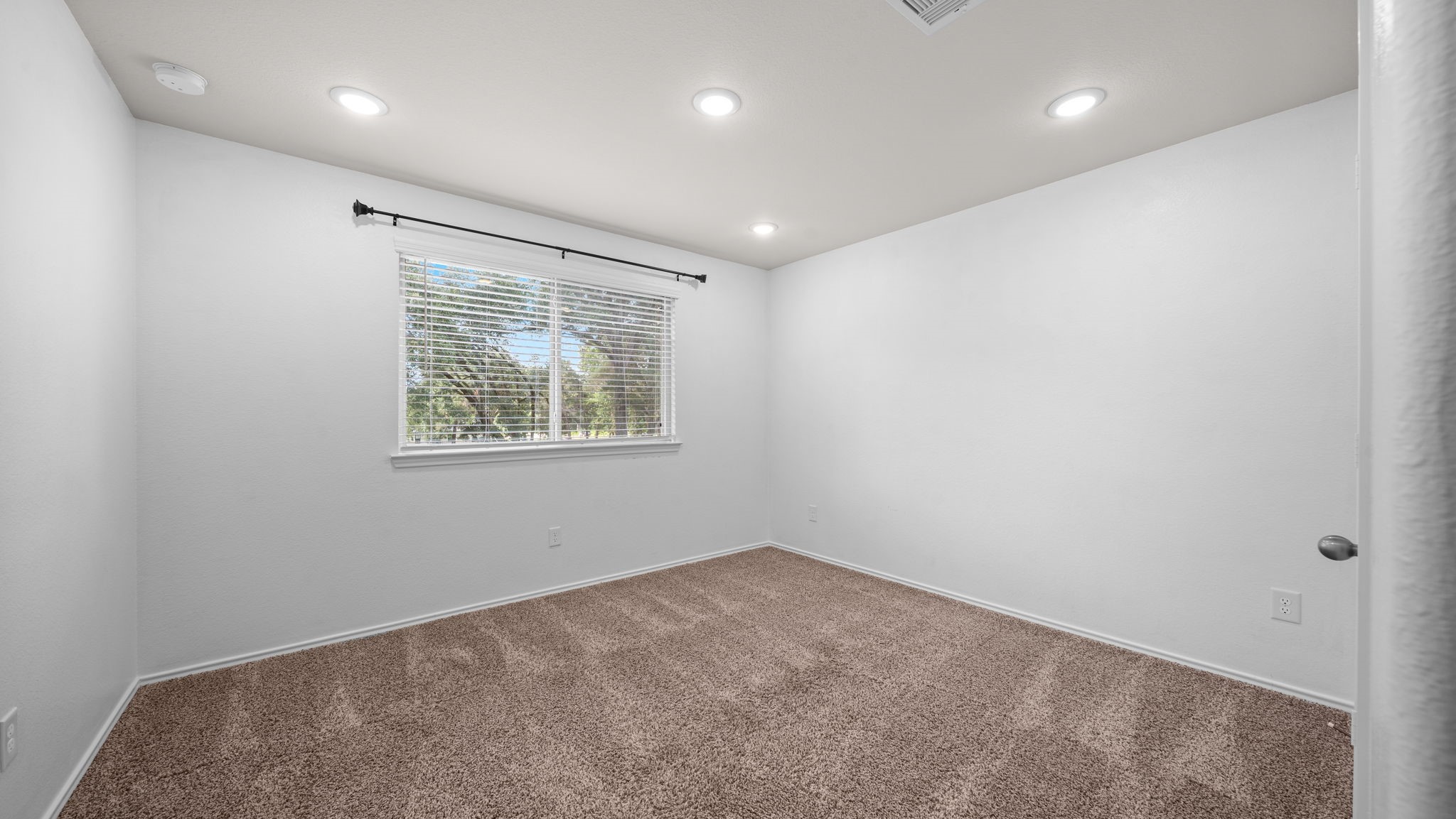 18140 Mail Rte Road Montgomery, TX 77316 - Photo 20 of 26 Bright secondary bedroom featuring plush carpeting, recessed lighting, and a large window with peaceful backyard views.