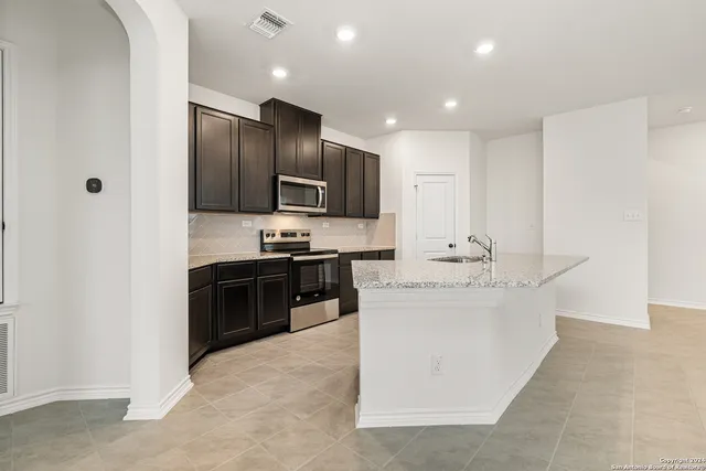 a large kitchen with kitchen island a sink stainless steel appliances and cabinets