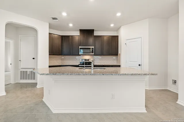 a large kitchen with kitchen island a sink stainless steel appliances and cabinets