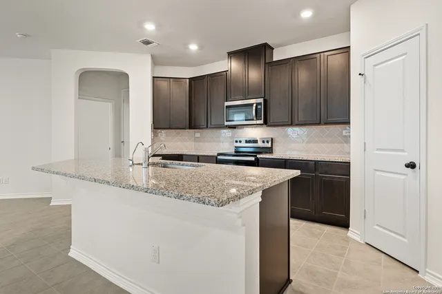 a kitchen with stainless steel appliances granite countertop a sink and a refrigerator