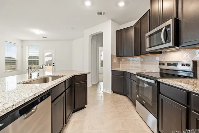 a kitchen with stainless steel appliances granite countertop a sink stove and refrigerator