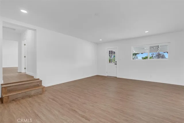 a view of a room with a ceiling fan and hardwood floor
