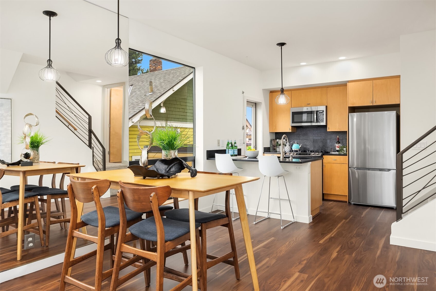 3818 South Hudson Street, Unit A Seattle, WA 98118 - Photo 8 of 31 a kitchen with stainless steel appliances kitchen island granite countertop a refrigerator a stove a microwave oven a dining table and chairs with wooden floor