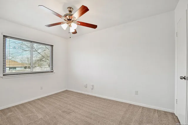an empty room with fan and windows