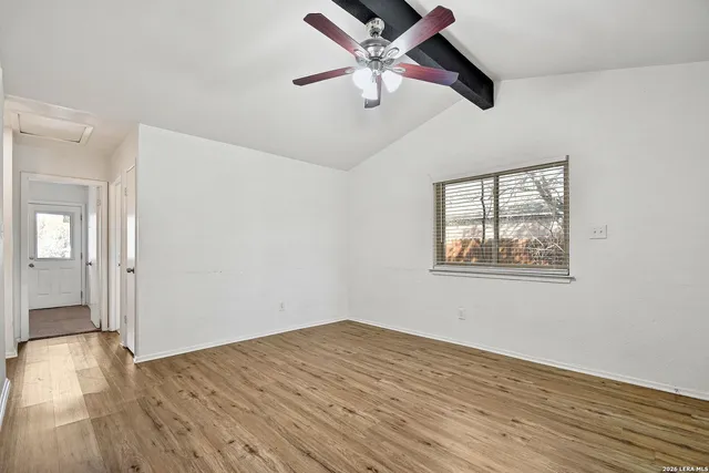 an empty room with wooden floor ceiling fan and windows