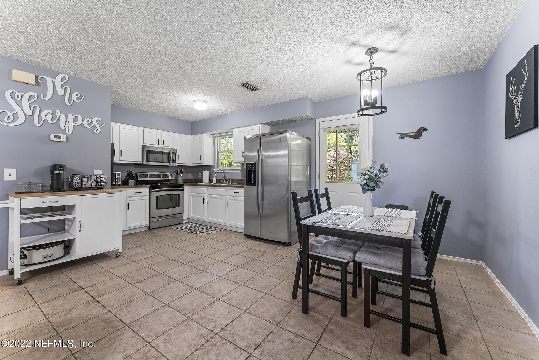 648 West Oliver Street Baldwin, FL 32234 - Photo 9 of 30 a kitchen with stainless steel appliances a table chairs refrigerator and cabinets
