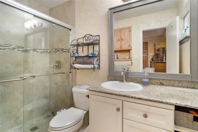 a bathroom with a granite countertop sink toilet a mirror and shower