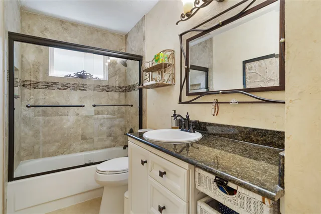 a bathroom with a granite countertop toilet sink and mirror