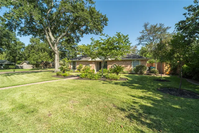 a view of a house with a big yard and large trees