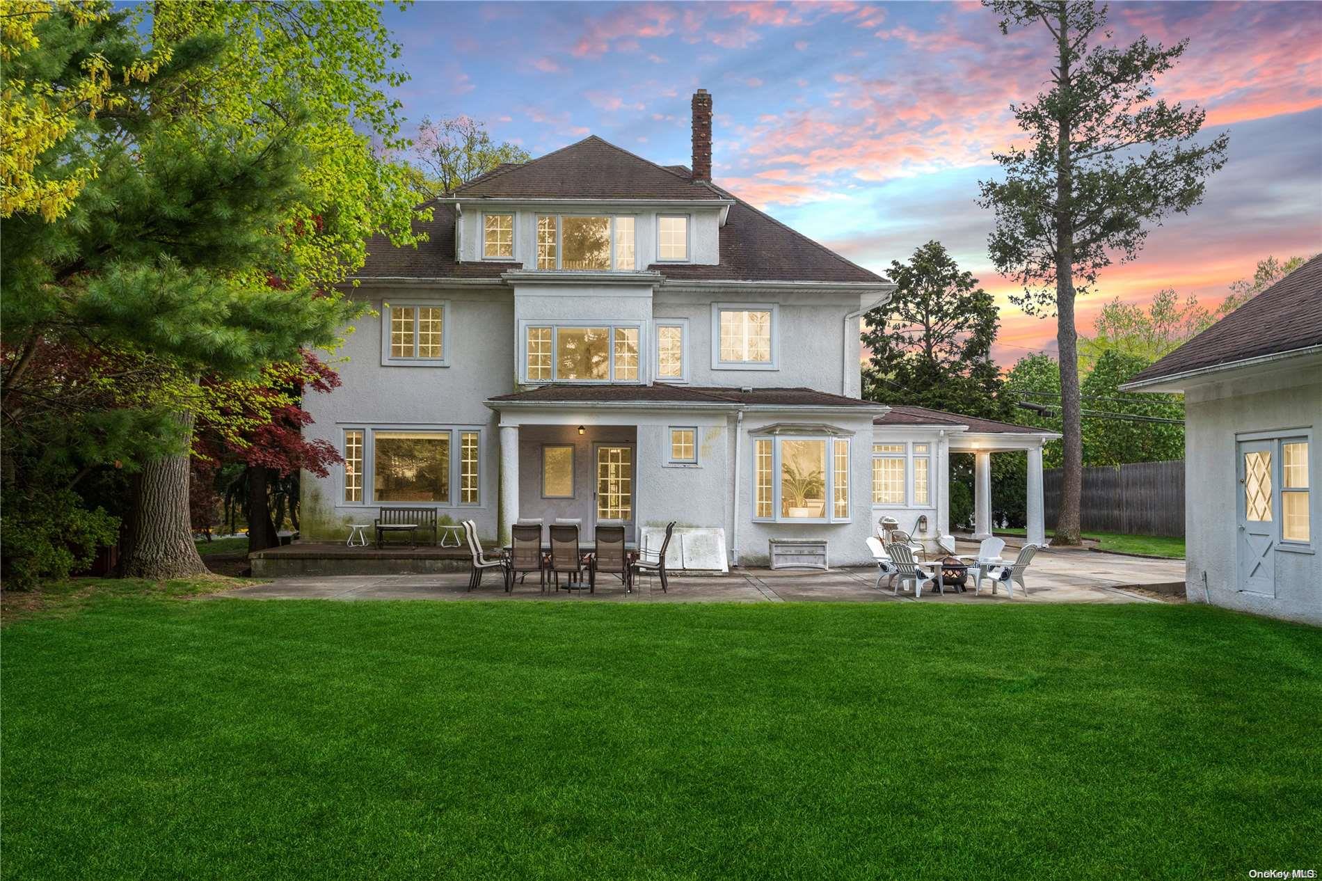 a front view of a house with a garden and trees