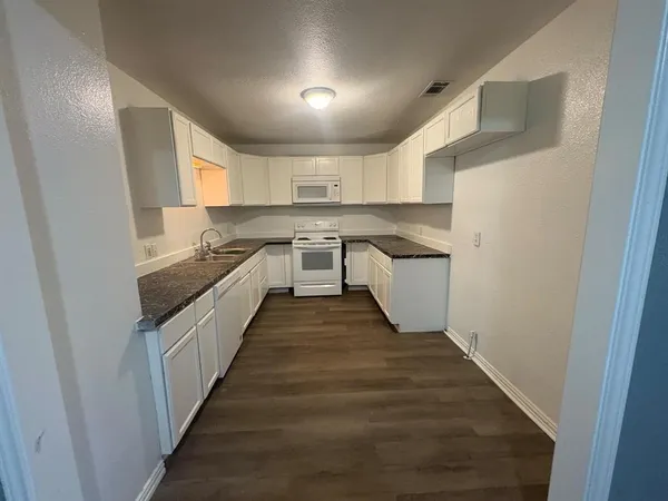 a kitchen with cabinets and wooden floor