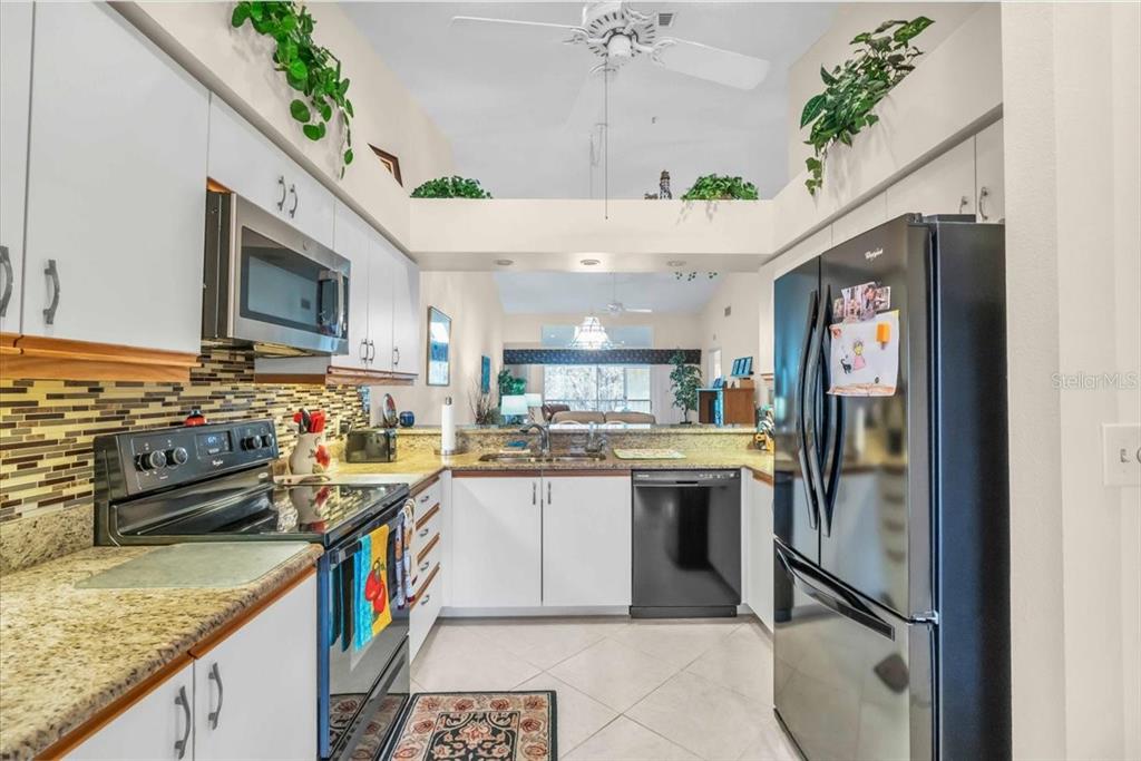 6713 Stone River Road, Unit 206 Bradenton, FL 34203 - Photo 15 of 58 a kitchen with stainless steel appliances granite countertop a sink a stove and a wooden cabinets