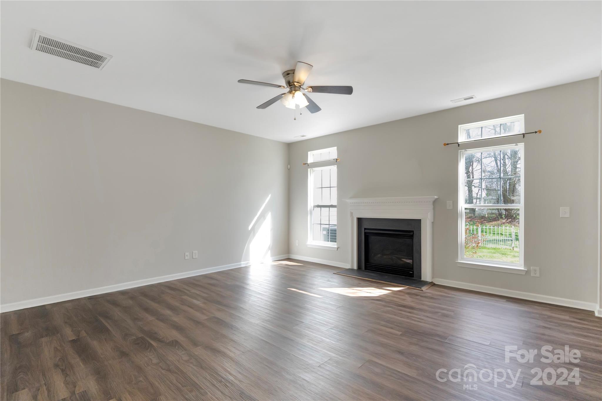 175 Snead Road Fort Mill, SC 29715 - Photo 5 of 26 an empty room with windows fireplace and a ceiling fan