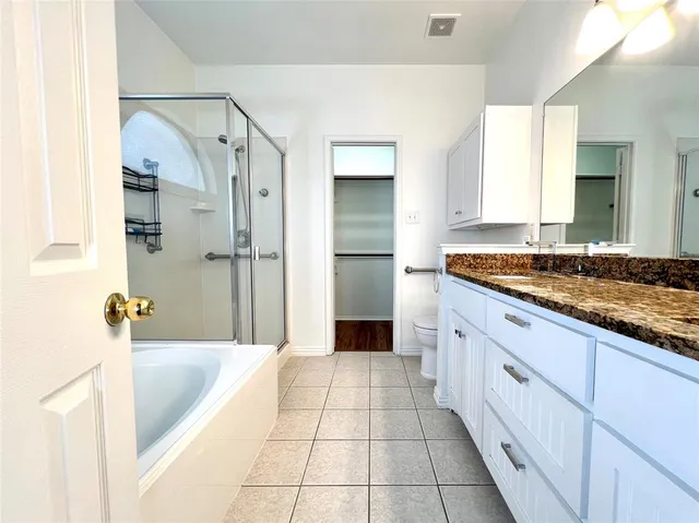 a spacious bathroom with a granite countertop sink a mirror and a bathtub