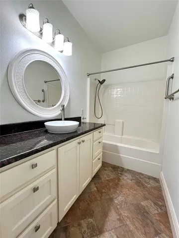 a bathroom with a granite countertop sink a mirror and a bathtub