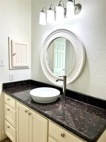 a bathroom with a granite countertop sink and a mirror