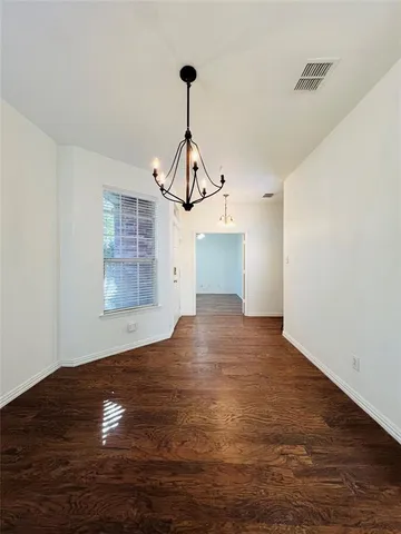 a view of empty room with wooden floor and windows