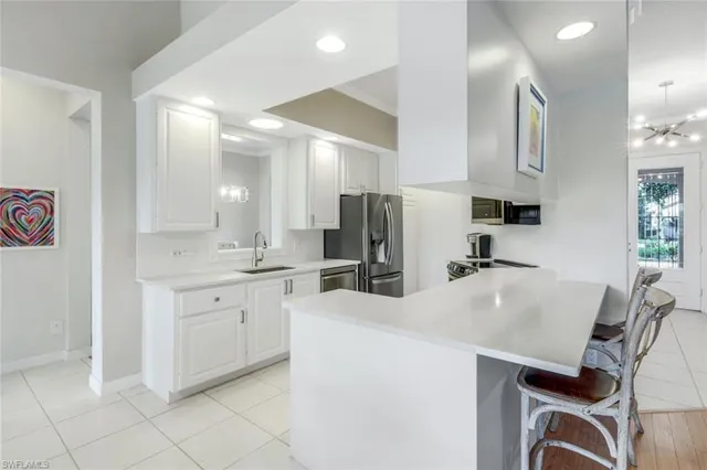 a kitchen with sink a refrigerator and chairs