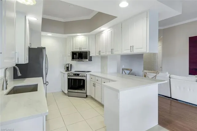 a kitchen with stainless steel appliances a stove a sink a microwave a refrigerator a white cabinets and couches