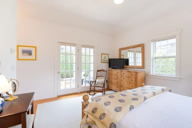 a bedroom with a bed a chair and a flat screen tv