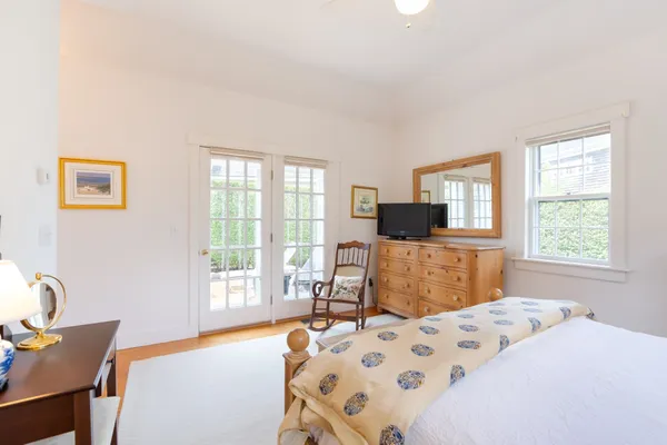 a bedroom with a bed a chair and a flat screen tv