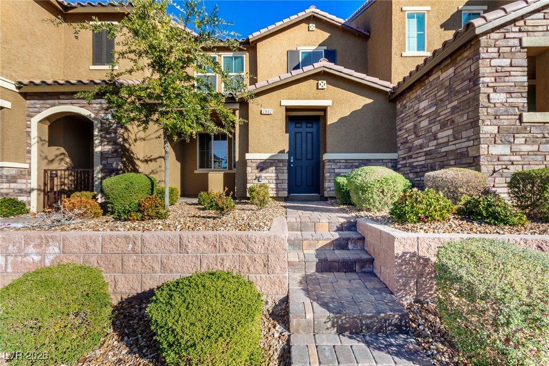 View of exterior entry featuring stone siding, stucco siding, and a tiled roof