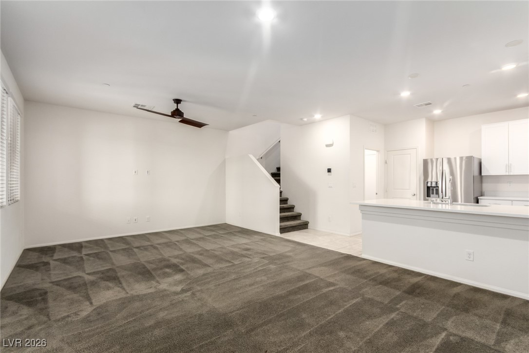 2862 Turnstone Ridge Street Henderson, NV 89044 - Photo 4 of 30 Unfurnished living room with a ceiling fan, light carpet, stairway, and recessed lighting