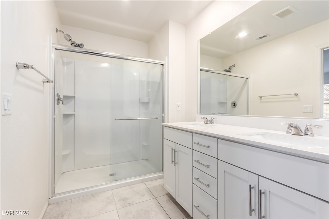 2862 Turnstone Ridge Street Henderson, NV 89044 - Photo 6 of 30 Bathroom featuring double vanity, light tile patterned floors, and a shower stall