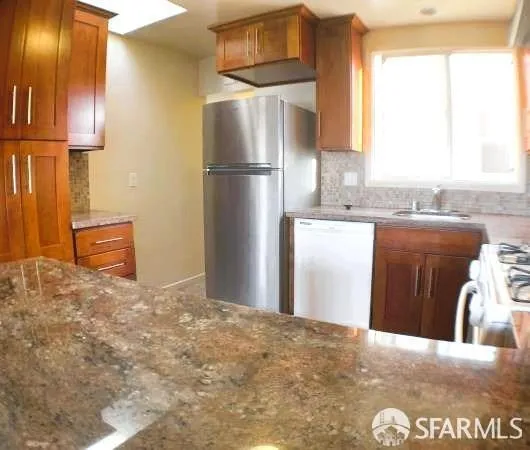 a kitchen with granite countertop a refrigerator and a sink