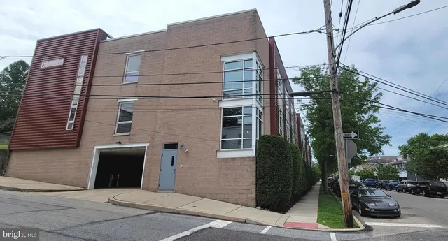 front view of a brick house with a yard and large tree