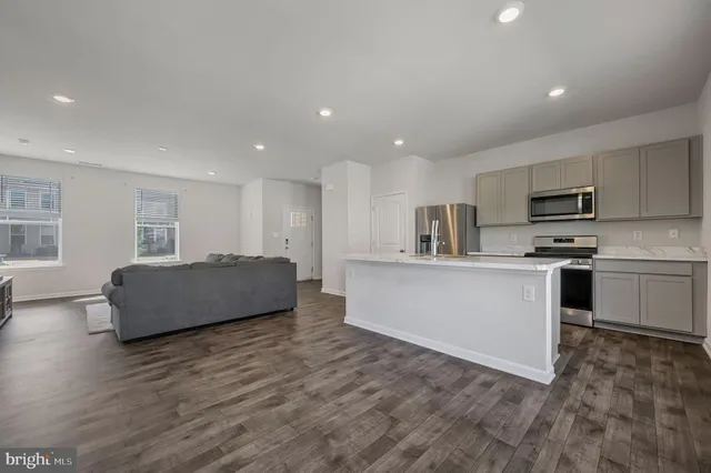 a large kitchen with kitchen island a sink a stove a microwave a center island and windows