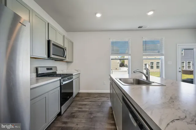 a kitchen with stainless steel appliances granite countertop a sink a stove and a refrigerator