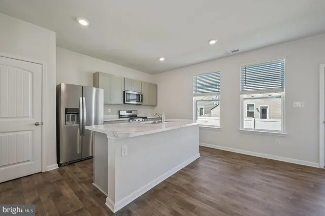 a kitchen with stainless steel appliances granite countertop a refrigerator a sink dishwasher a stove and white countertops with wooden floor