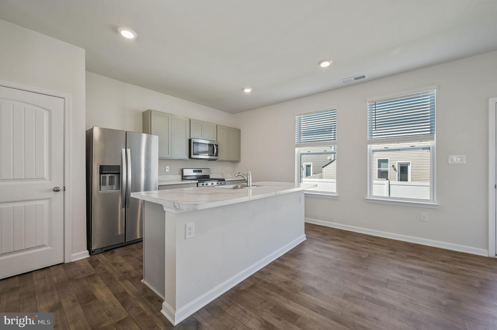 49 Citrus Drive Camden Wyoming, DE 19934 - Photo 18 of 27 a kitchen with stainless steel appliances granite countertop a refrigerator a sink dishwasher a stove and white countertops with wooden floor
