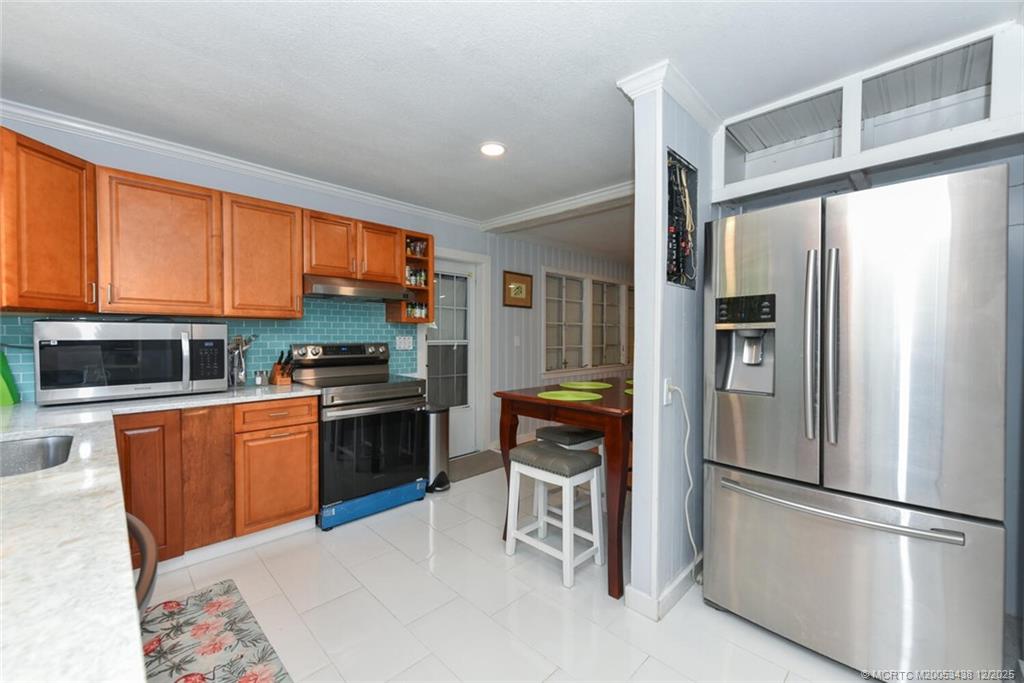 817 Southwest St Lucie Crescent Stuart, FL 34994 - Photo 22 of 25 a kitchen with stainless steel appliances granite countertop a refrigerator a stove a sink and a microwave
