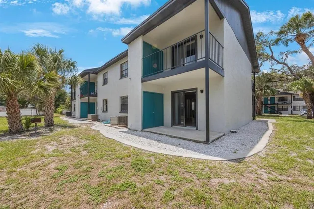 a view of a white house with a large tree and wooden fence