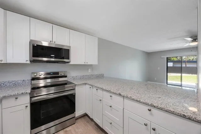 a kitchen with granite countertop a stove a microwave a sink and cabinets